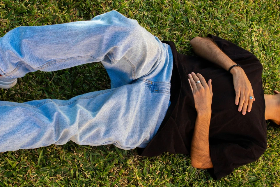 A man laying in the grass with his hands on his chest